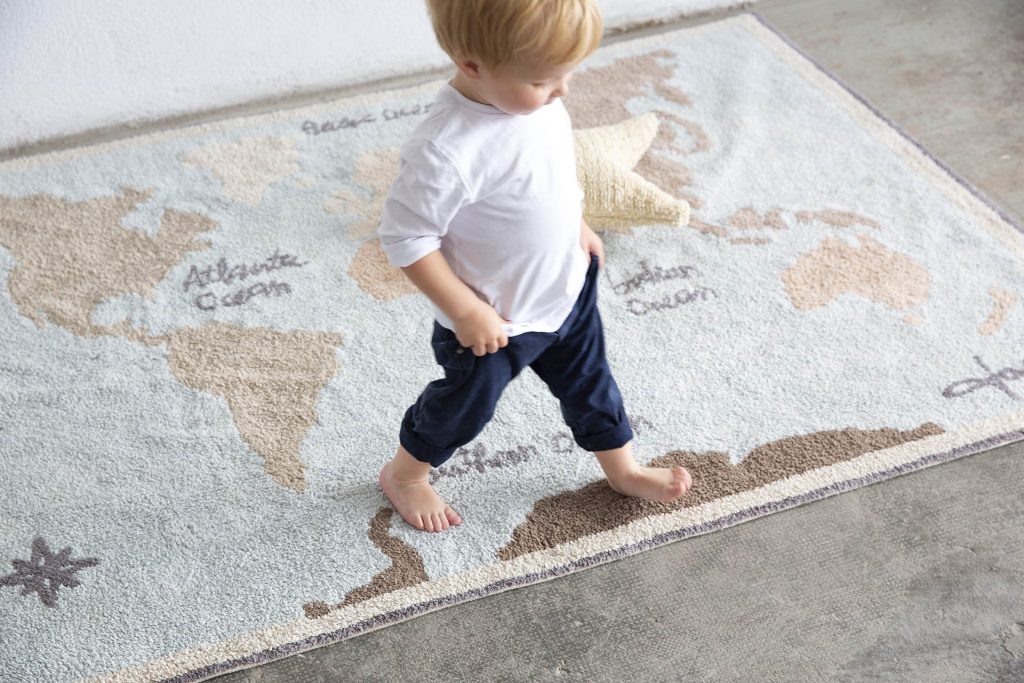 Baby walking on a rug.