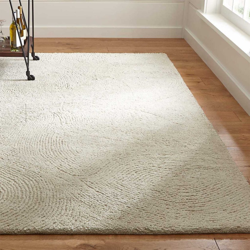 Alfredo Ivory Wool Rug on a Hardwood Floor.